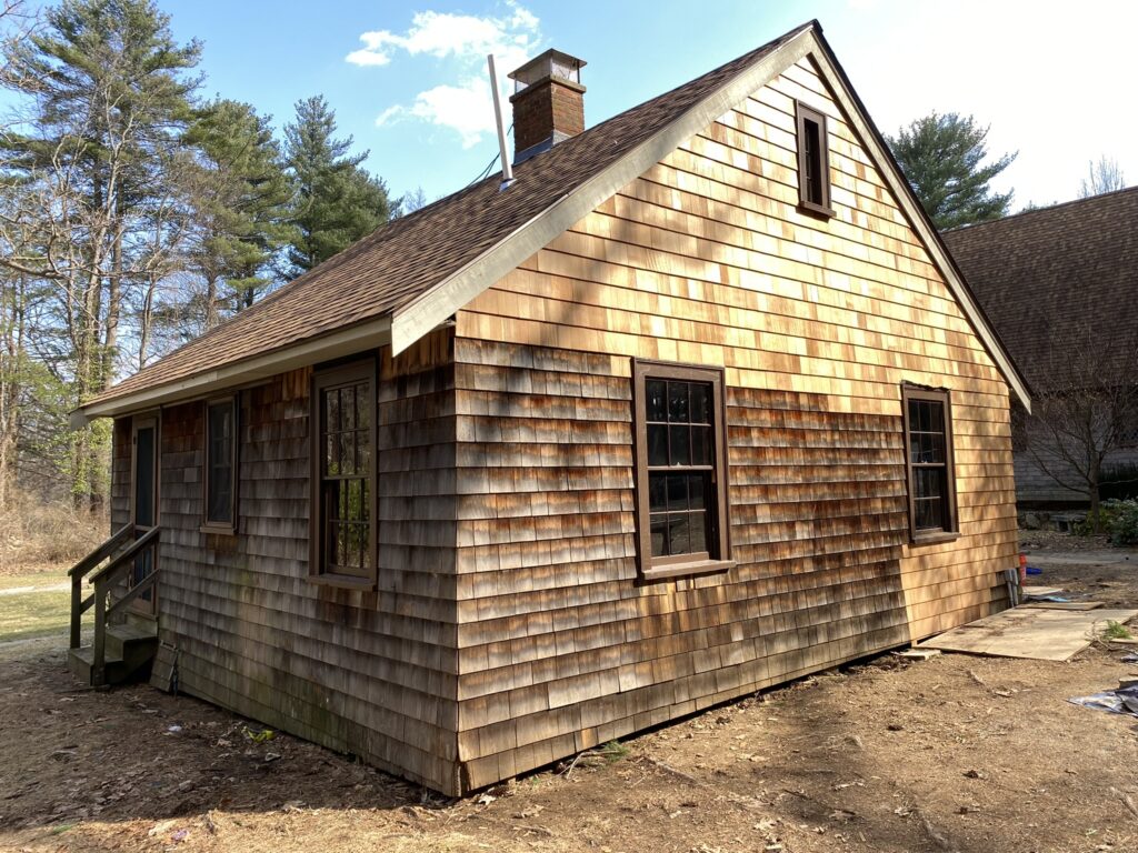 new wood shingle siding on a repaired cabin 